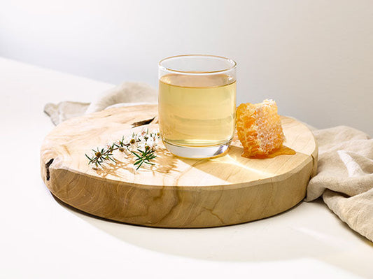 glass of manuka honey apple cider vinegar water on a round block of wood