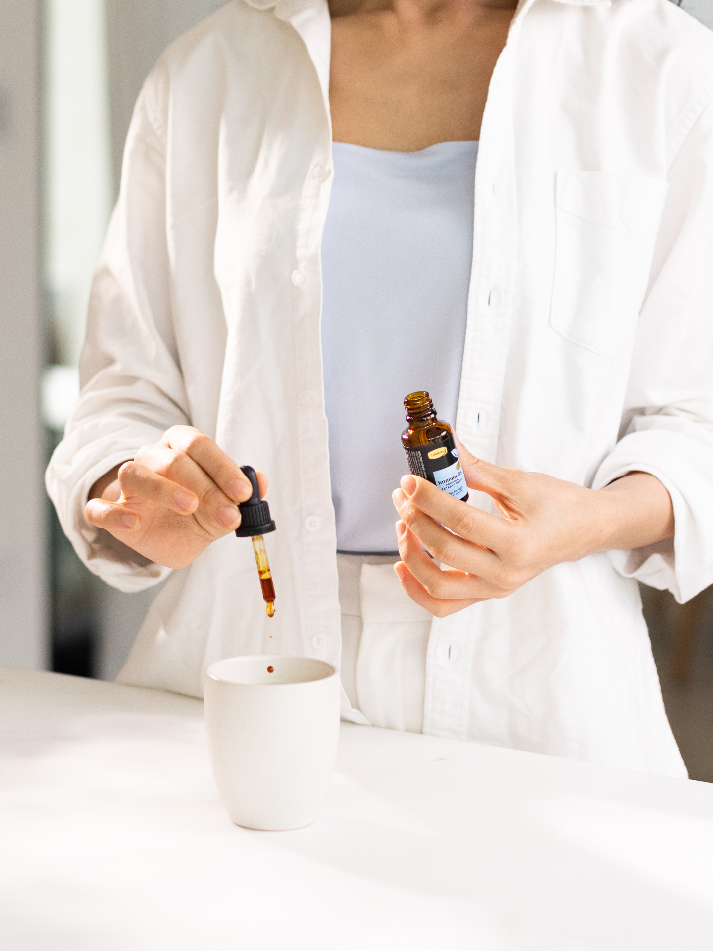 a woman adding bee propolis drops to her drink