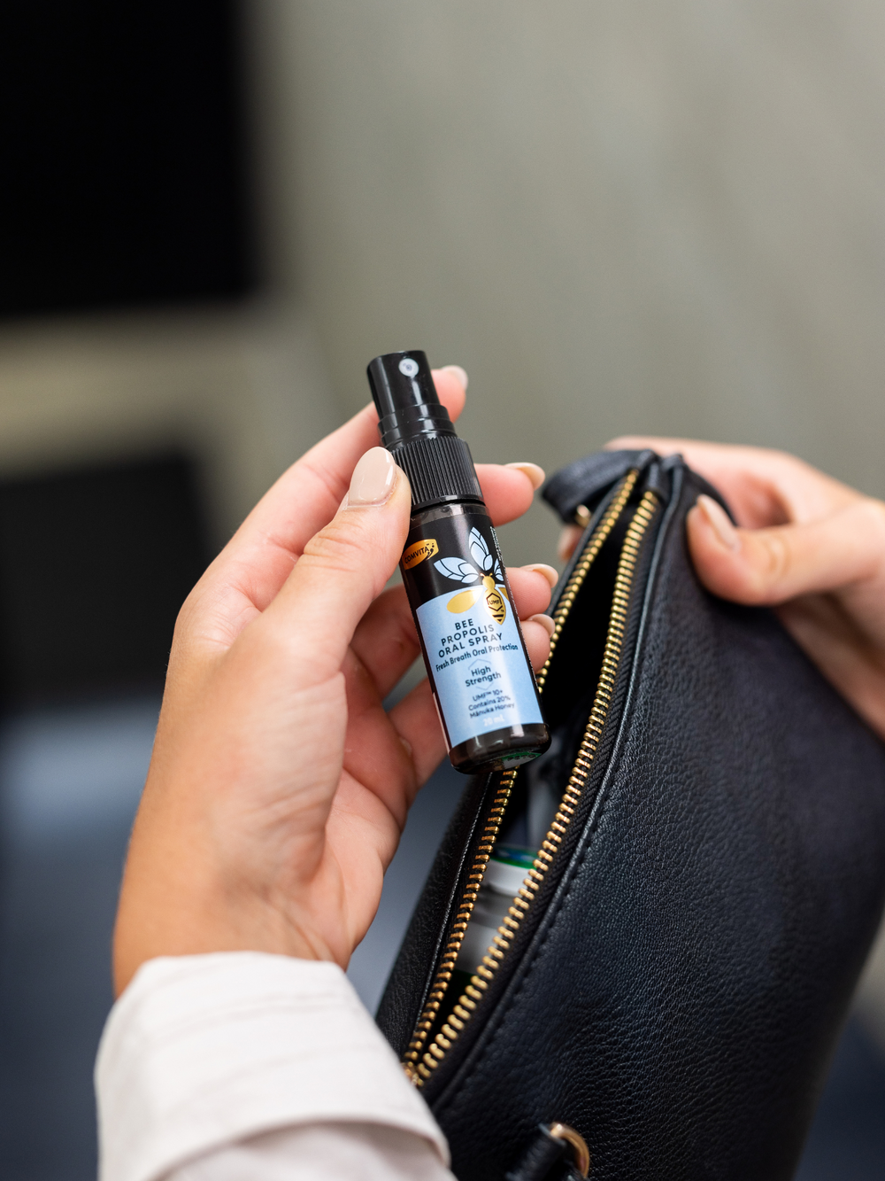 a woman putting bee propolis oral spray into her handbag