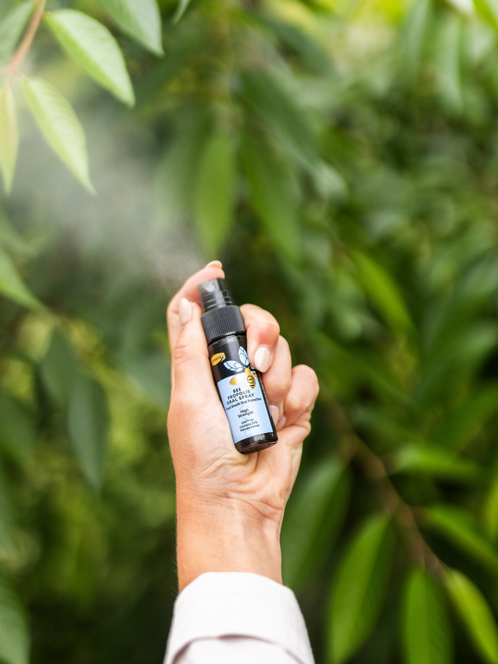 a woman spraying bee propolis oral spray