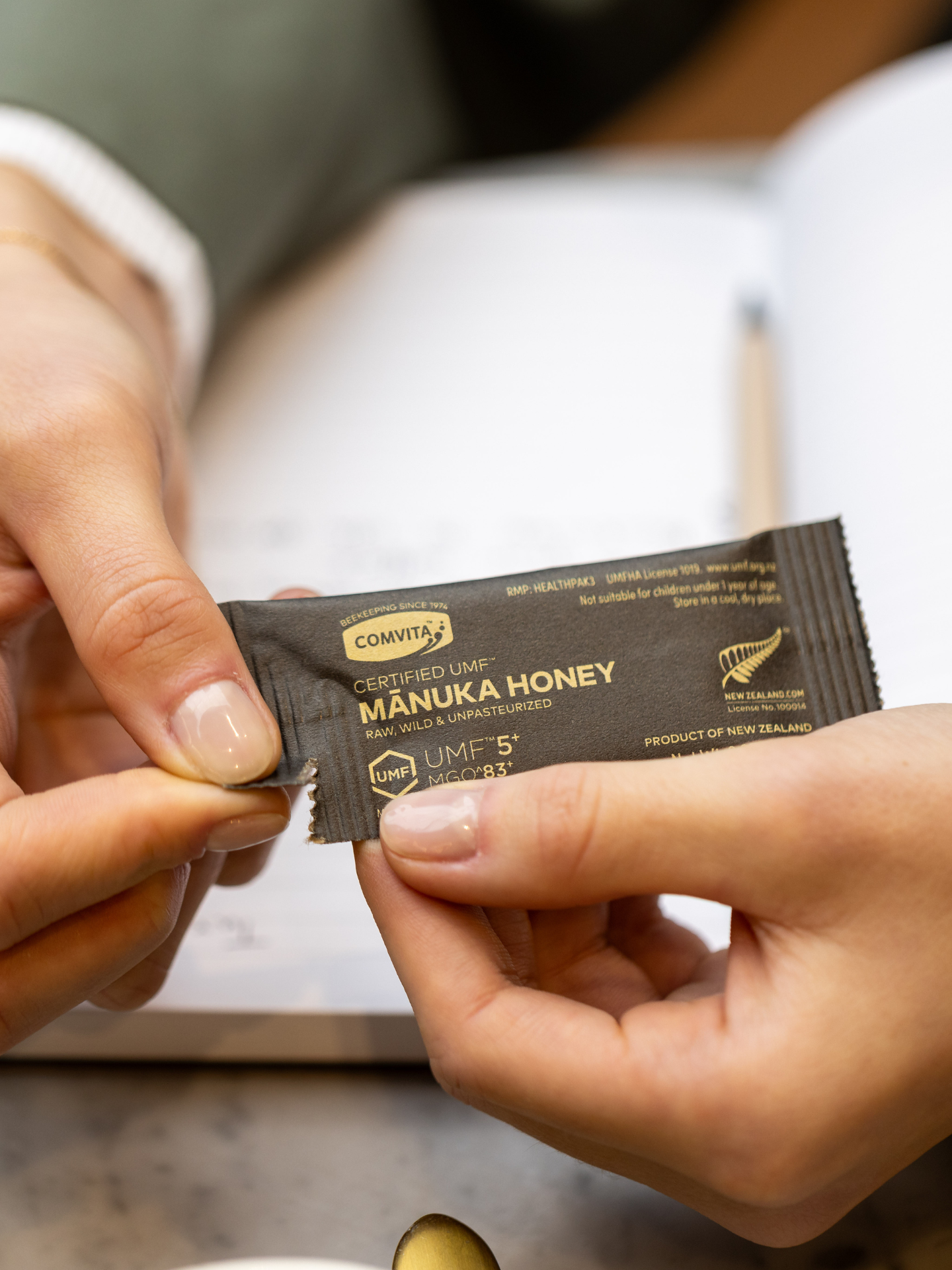 a woman tearing open a manuka honey single