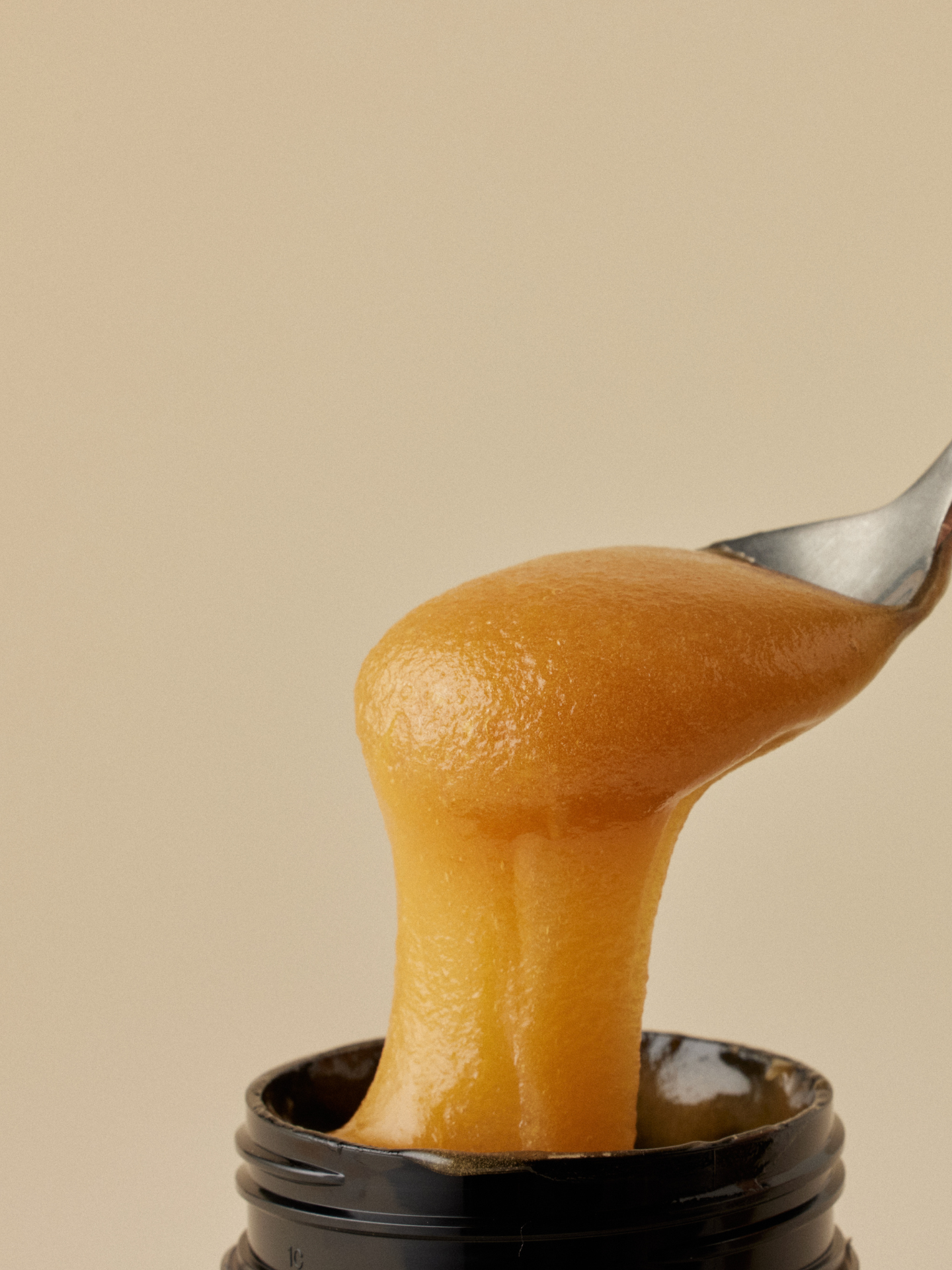 a spoon of manuka honey dripping into a jar