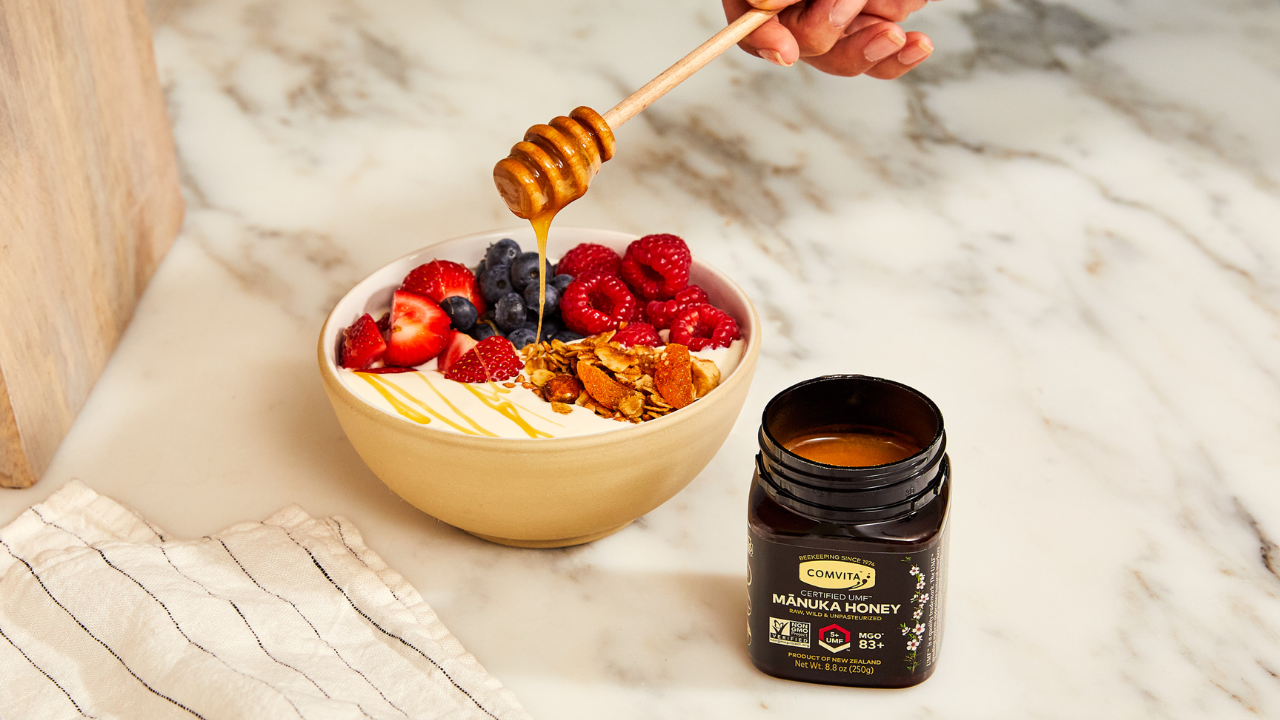 bowl of yogurt berries and honey on a spoon with jar