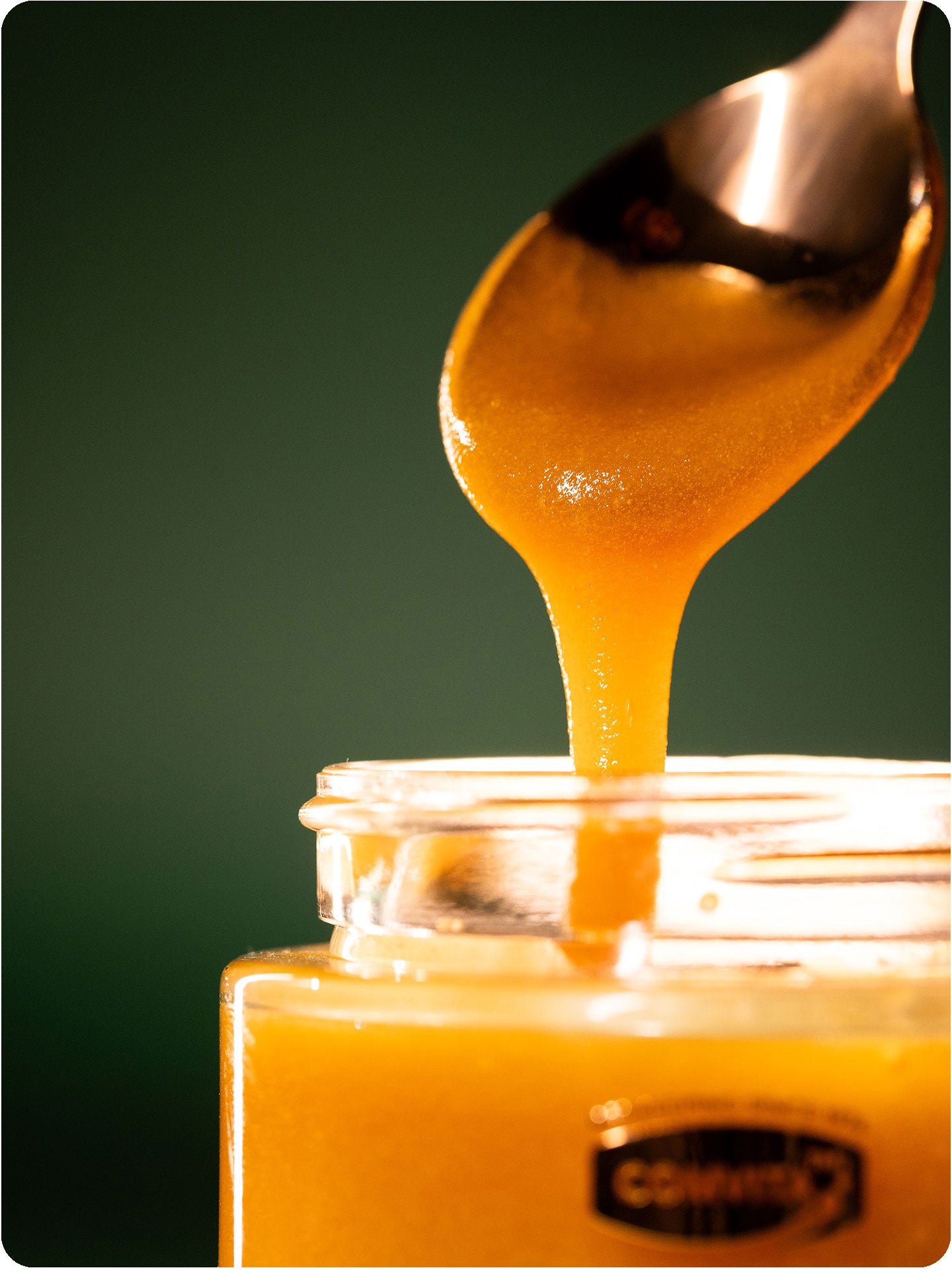 umf 25 manuka honey dripping from spoon to jar