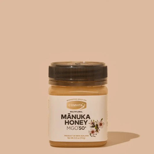 Jar of Manuka Honey with Comvita branding on a beige background