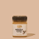 Jar of Manuka Honey with Comvita branding on a beige background