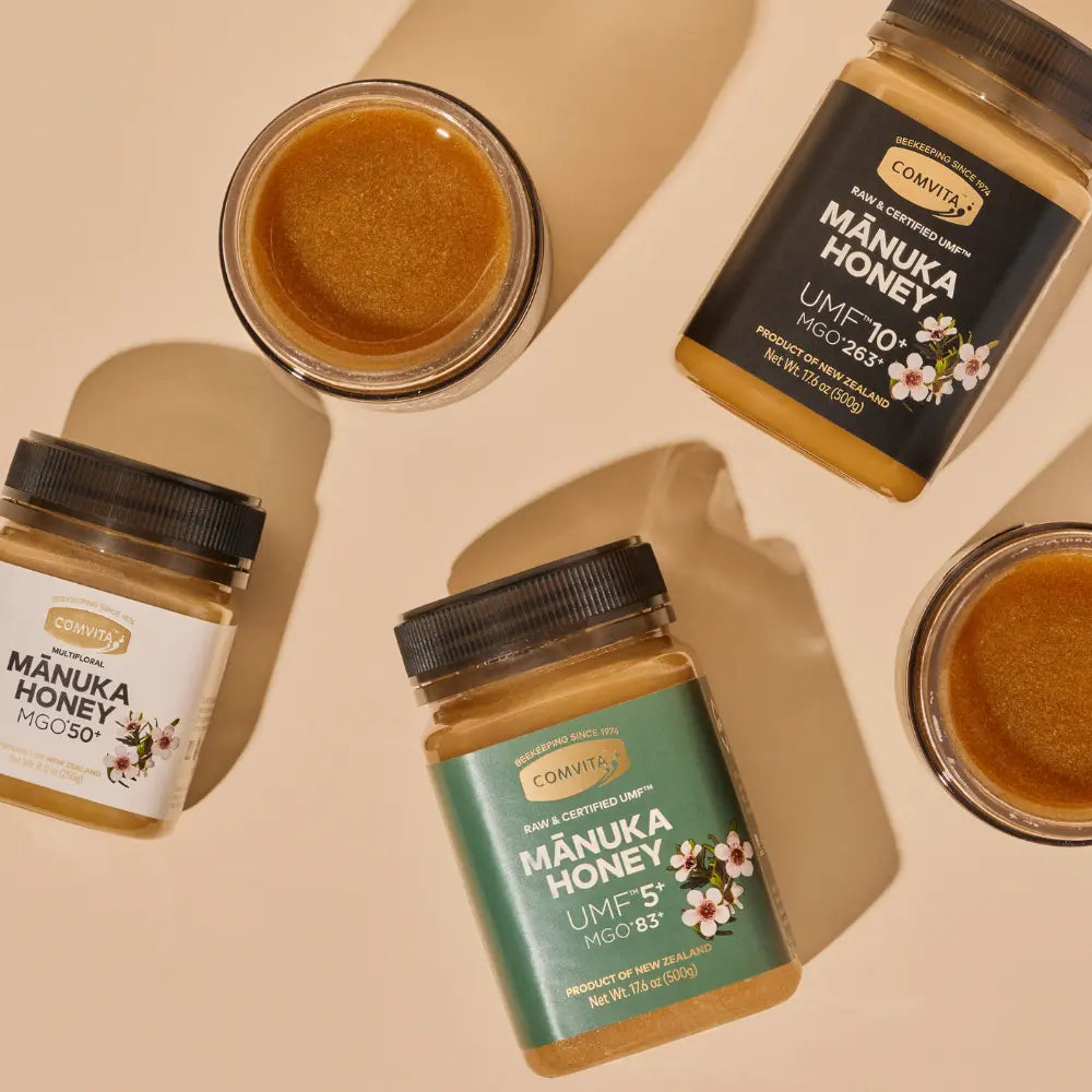 Jars of Manuka honey with visible labels on a beige background
