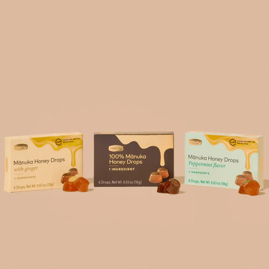 Three boxes of Manuka Honey Drops with honey drops displayed in front on a beige background