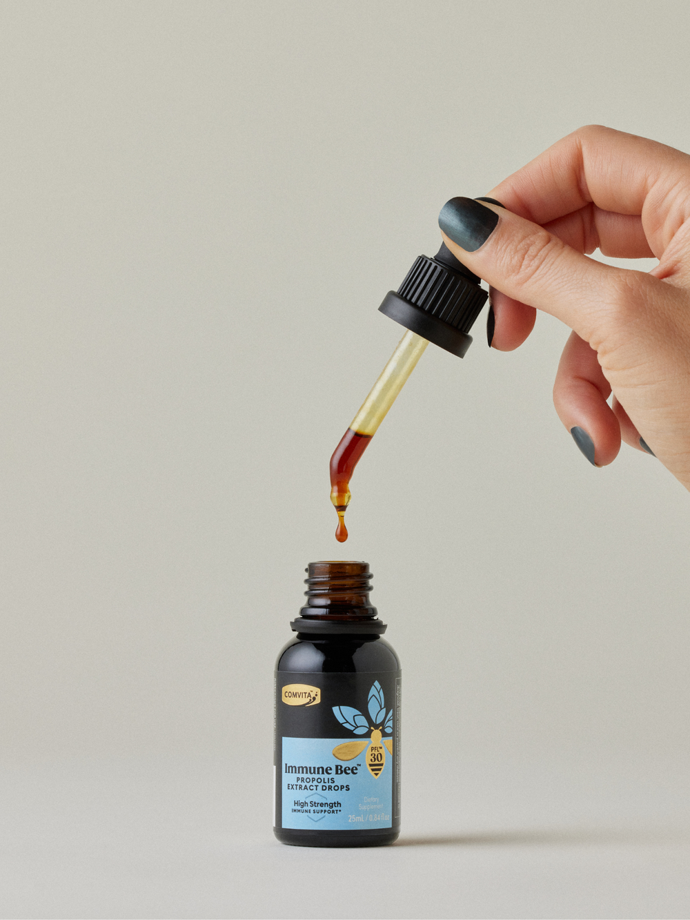 a woman dripping immune bee propolis extract drops into the bottle