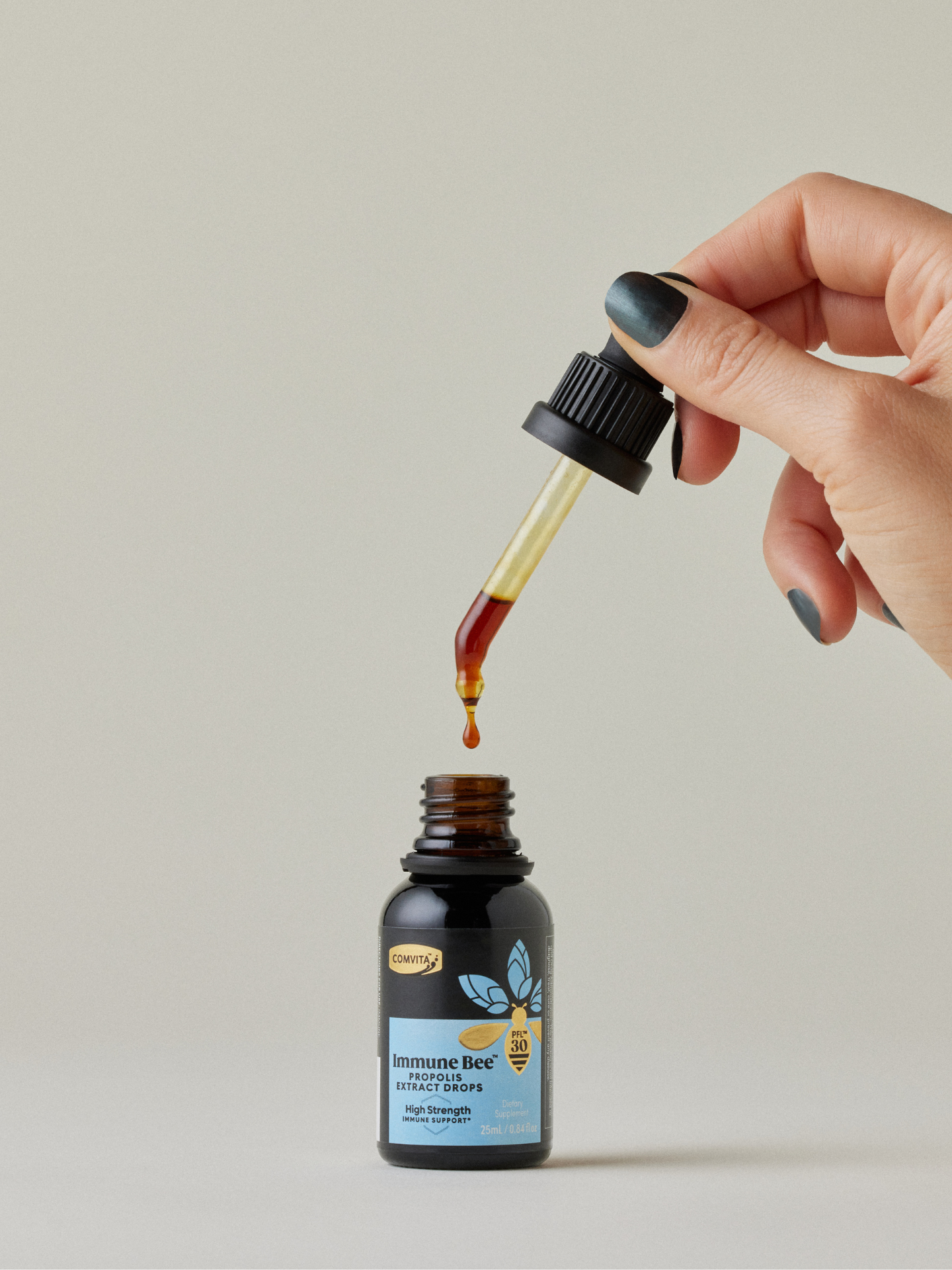 a woman dripping immune bee propolis extract drops into the bottle