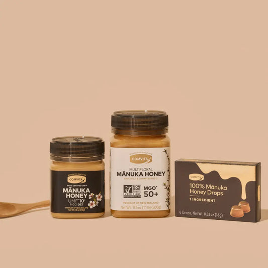 Manuka honey products including jars, honey drops and a wooden honey spoon on a beige background