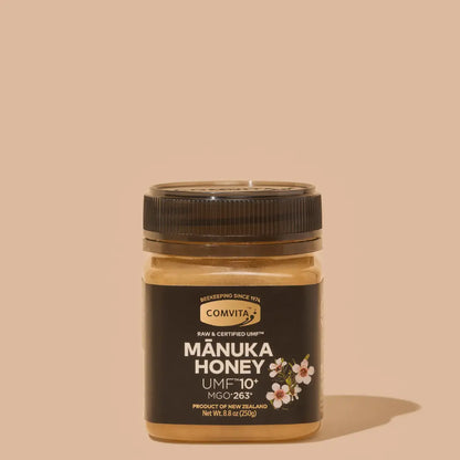 Jar of Manuka Honey with Comvita branding on a beige background