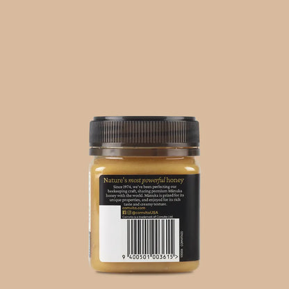 Jar of manuka honey with a black lid on a beige background