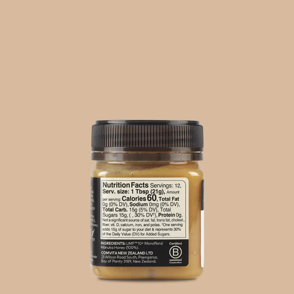 Jar of manuka honey with nutrition label on a beige background