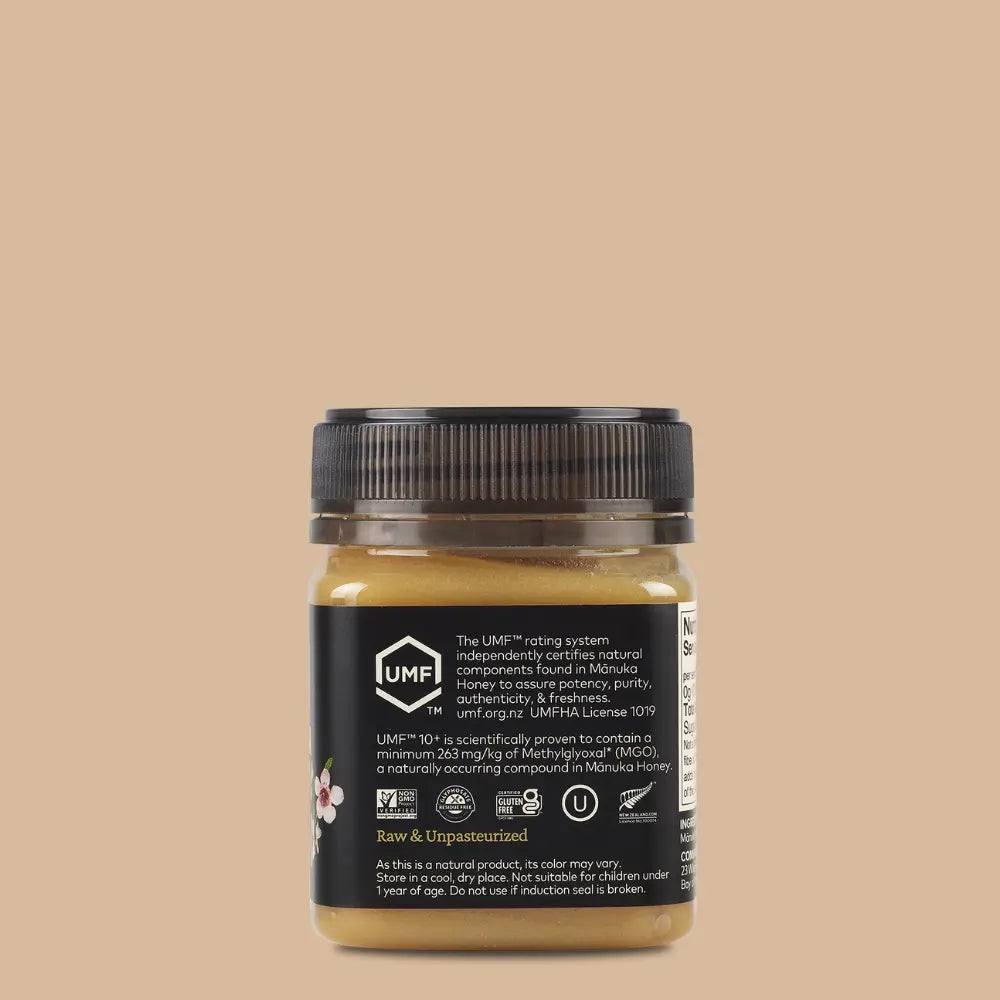 Jar of UMF manuka honey with black lid on a beige background
