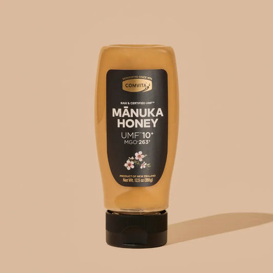 Manuka honey bottle with Comvita label on a beige background
