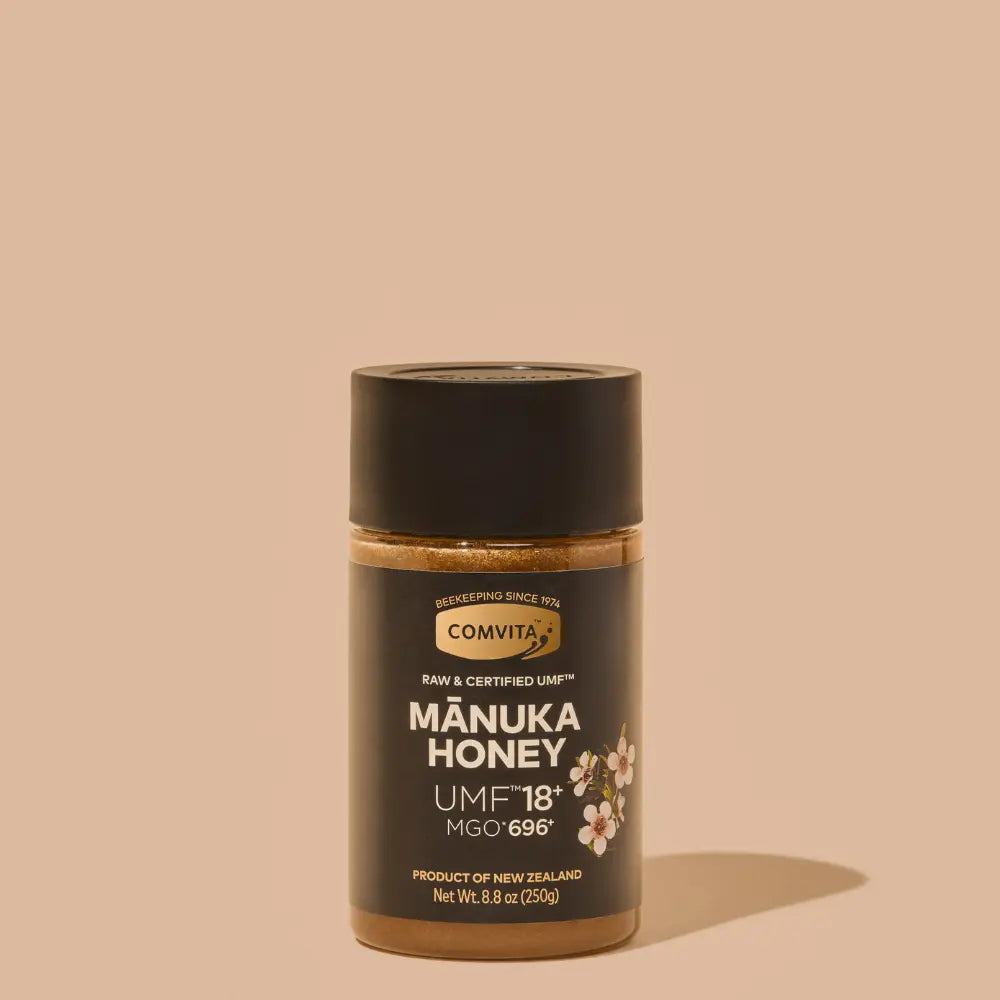 Jar of Comvita Manuka Honey on a beige background