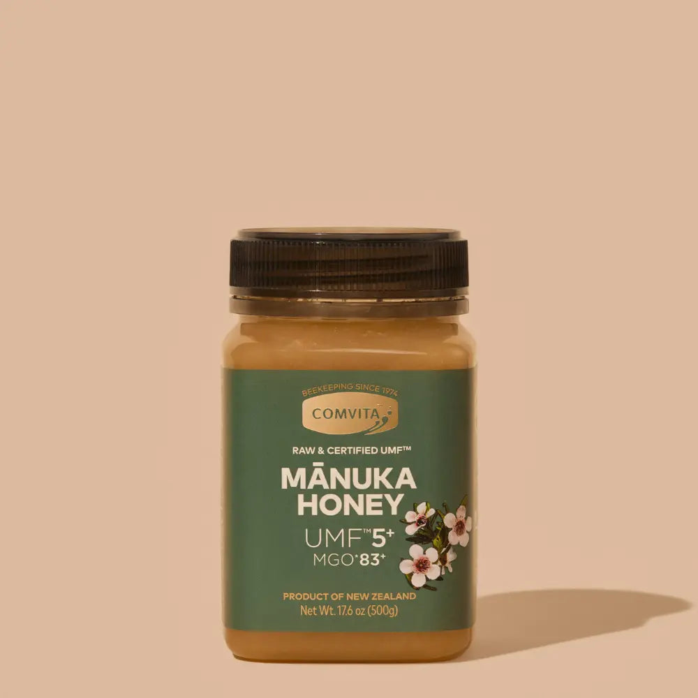 Jar of Comvita Manuka Honey UMF5 on a beige background