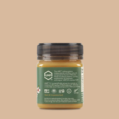 Jar of manuka honey with a green label on a beige background