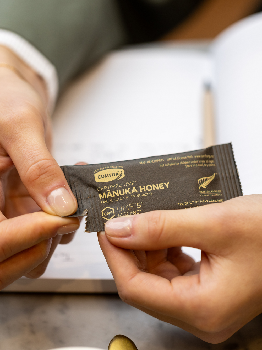 a woman tearing open a manuka honey single